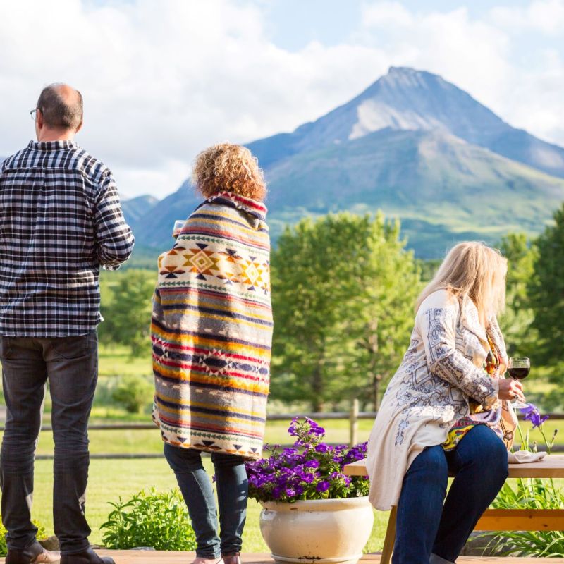 a group of people sitting on a bench with a mountain in the background