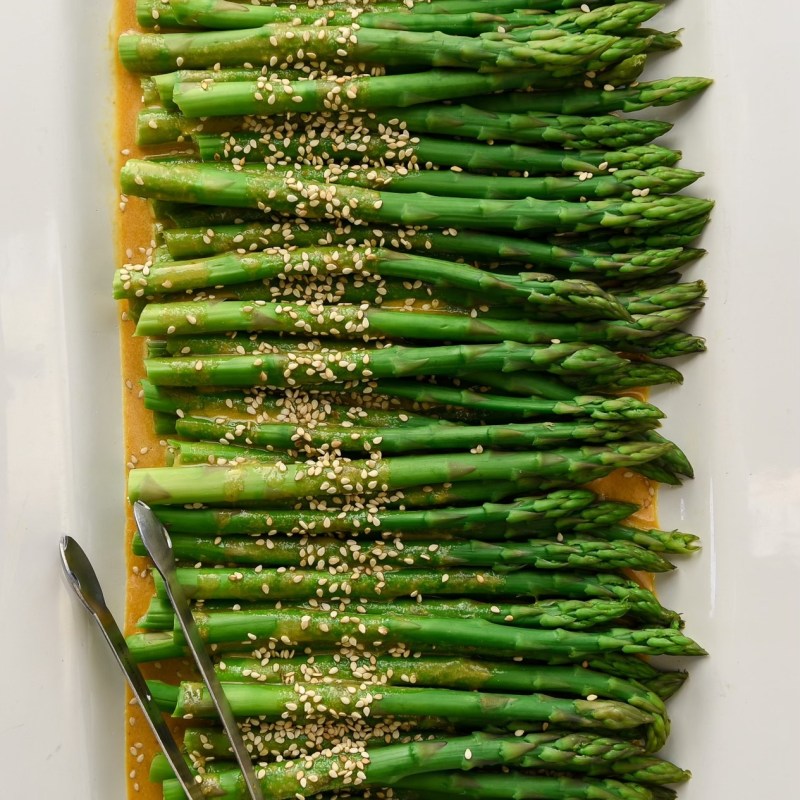 a bunch of green asparagus sprinkled with sesame seeds