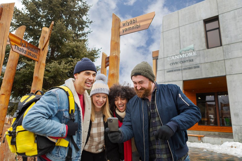 Four friends in winter clothing taking a selfie outside Canmore Civic Centre.