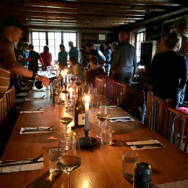 Candlelit dining table with people gathered around, indoors with rustic ambiance.