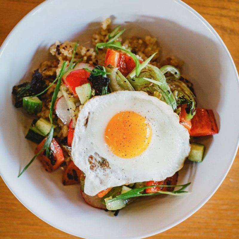 Bowl of fried rice with vegetables and a sunny-side-up egg on top.