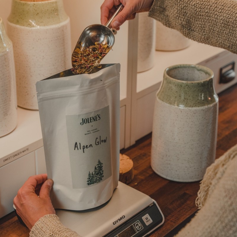 Person pours tea into a labeled bag on a digital scale.