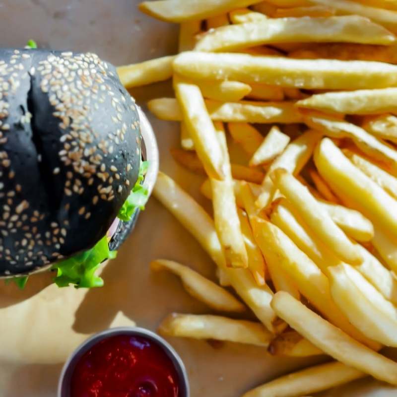 Charcoal bun burger and fries with ketchup.