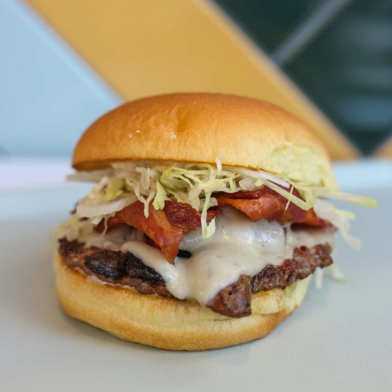 Cheeseburger with bacon, lettuce on a bun.