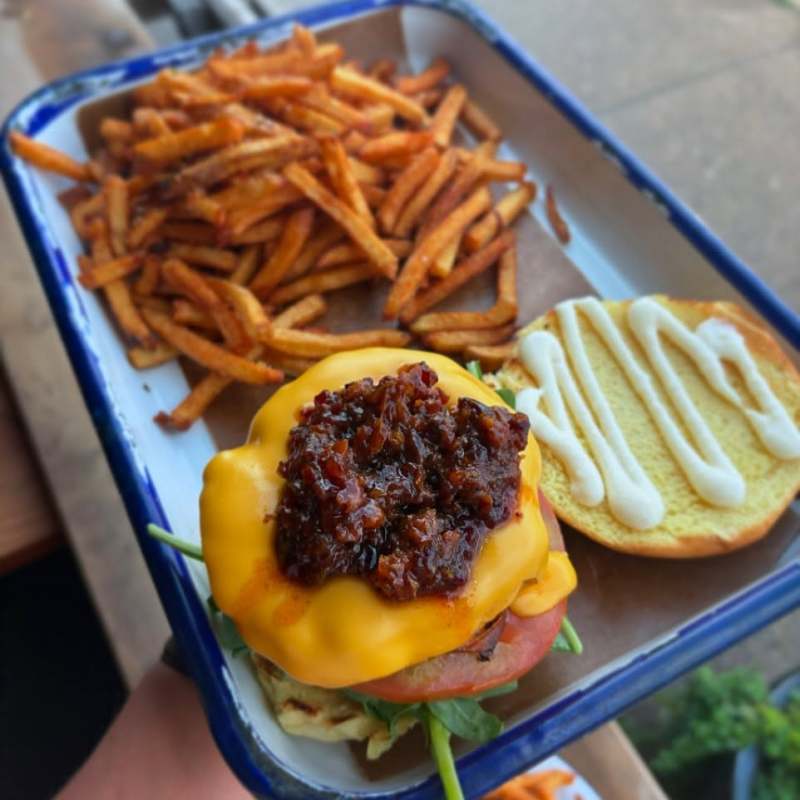 Cheeseburger with bacon jam and fries on a metal tray.
